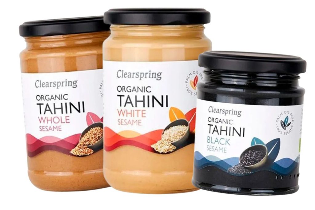 Tre varianter af Clearspring Tahini: hel sesam, hvid sesam og sort sesam i glas med etiketter.