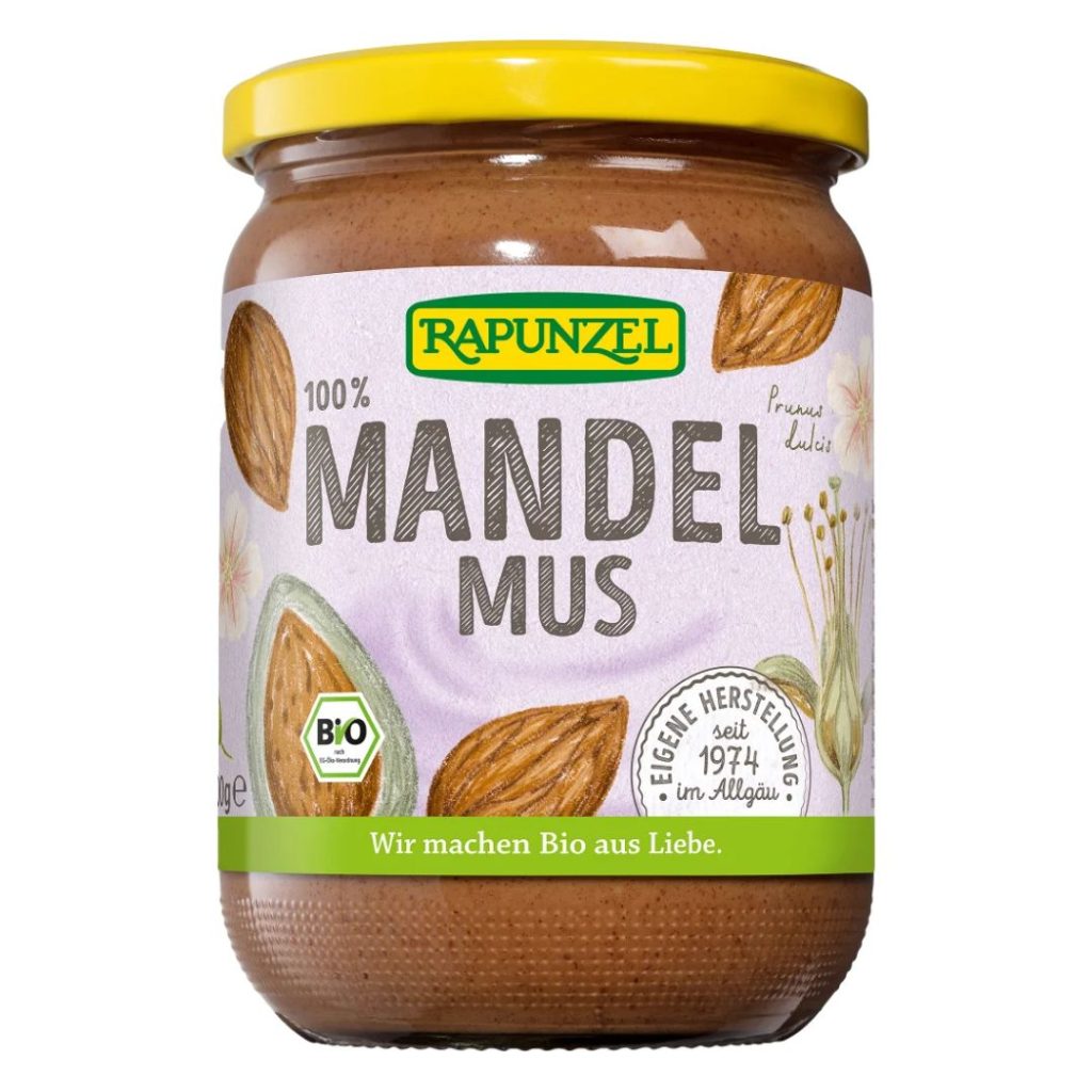 Glas med Rapunzel Mandelmus, gul låg og naturlig emballage.