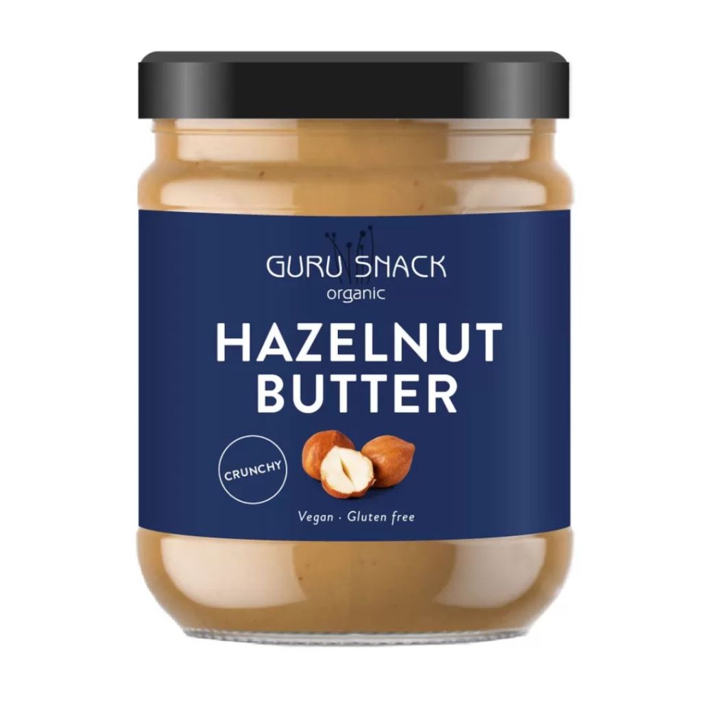 Glas med Guru Snack Hazelnut Butter Crunchy og blå etiket.
