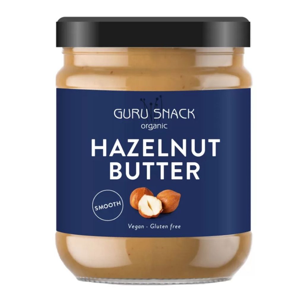Glas med Guru Snack Hazelnut Butter Smooth med blå etiket.