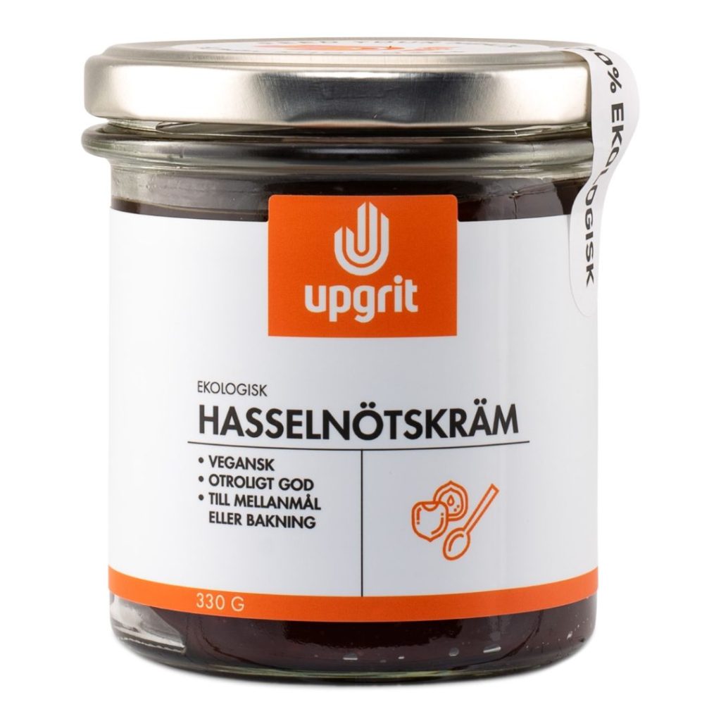 Glas med Upgrit økologisk hasselnøddecreme med hvid og orange etiket.