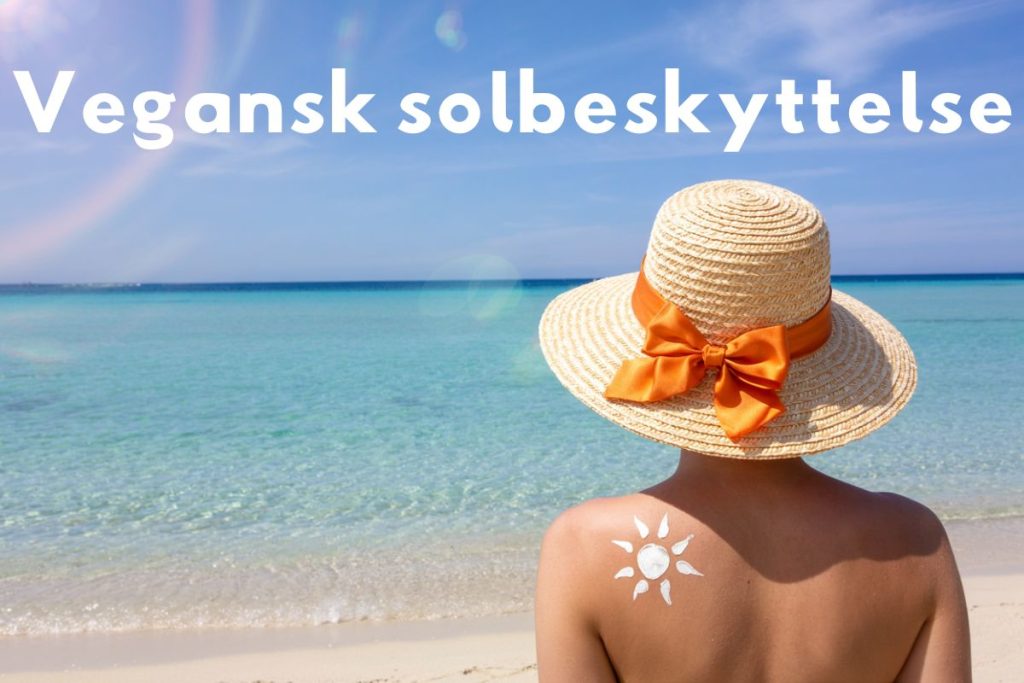 Person med solhat og solcreme i form af en sol tegnet på skulderen, ved havet med teksten 'Vegansk solbeskyttelse'.